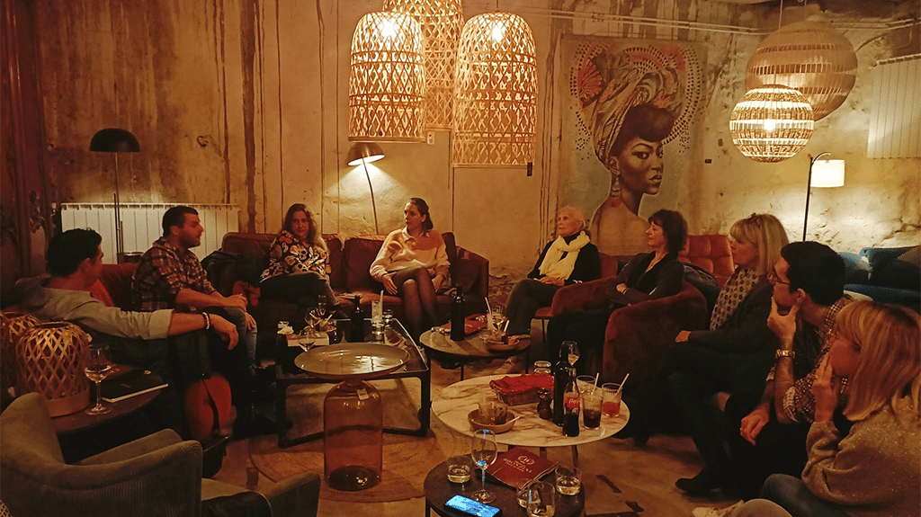 Photo d'une reading party, des personnes assises sur des canapés discutent.