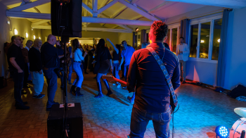Photo d'un guitariste de dos avec des personnes qui dansent devant lui.